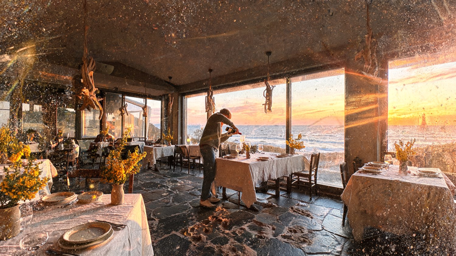 Coastal restaurant with linen-laid tables and tall windows to the sea